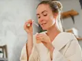 Frau mit einem Tropfen Serum in der Pipette, bereit für ihre Hautpflege-Routine. Ob Retinol oder Hyaluron, sie wählt das Beste für ihre Haut.