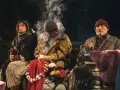 Antygona w Nowym Jorku: bohaterowie siedzą na ławce, otoczeni dymem i kwiatami, w ponurej atmosferze.