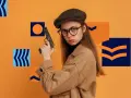 Dziewczyna w kaszkiecie i okularach trzyma pistolet. Może to symbolizować jej zainteresowanie kryminalistyka studia wymagania.