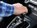 Dłoń na dźwigni zmiany biegów w aucie z funkcją auto hold i manualną skrzynią.
