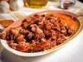Oreja de cerdo crujiente y dorada servida en un plato con puré naranja.