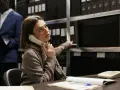 Kobieta, pracująca jako kryminolog, odbiera telefon w archiwum pełnym akt.