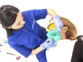 Dentystka zakłada koferdam, zieloną osłonę izolującą ząb pacjentki. To nowoczesne rozwiązanie w stomatologii.