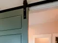 Trasformare porta battente in scorrevole: una porta verde acqua con binario nero, un'elegante soluzione moderna per ottimizzare gli spazi.