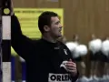 Andrzej Marszałek, trener, wpatrzony w boisko, z ręką na słupku bramki. W tle kibice.