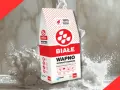 Białe wapno hydratyzowane w worku, otoczone chmurą pyłu. Idealne do prac budowlanych.