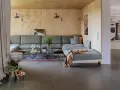 Sofá modular gris, alfombra oriental, mesa de centro de cristal y detalles de interiorismo años 60.
