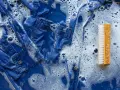 Niebieska koszula w pianie, obok szczoteczka do ubrań, idealna by dowiedzieć się, czym sprać smar.