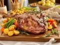 Gigot d'agneau cuisson lente 4 heures, rôti à la perfection, servi avec des pommes de terre rôties, des carottes et des haricots verts.