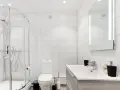 Baño moderno con ducha, inodoro y lavabo. La ventilación del baño es discreta en la pared, asegurando un ambiente fresco.