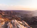 Wąwóz Fish River w Namibii, z rzeką wijącą się w dole. Zachodzące słońce maluje skały na ciepłe barwy.