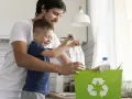 Padre e hijo reciclando botellas de plástico en un contenedor verde. Enseñando conciencia ecológica desde pequeños.
