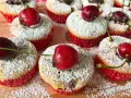 Saftige kirsch muffins, bestäubt mit Puderzucker und garniert mit frischen Kirschen. Ein süßer Genuss!