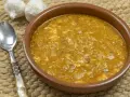 Sopa de ajo tradicional en cuenco de barro, con ajos y cuchara al lado.