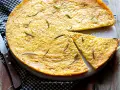 Una torta dorata, profumata al rosmarino, perfetta come ricetta con farina di ceci. Una fetta è già stata tagliata.