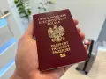 Polski paszport w dłoni. Czy do USA potrzebna jest wiza? Podróż w toku, walizka czeka.