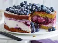 Saftige Heidelbeertorte mit Joghurt-Füllung, garniert mit frischen Beeren und Puderzucker. Ein Genuss für Augen und Gaumen.