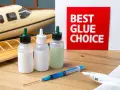 Three bottles of model glue and a syringe sit on a wooden surface next to model airplanes. A red sign reads "BEST GLUE CHOICE.
