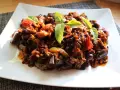 Un piatto di saporita caponata di melanzane, guarnita con foglie di basilico fresco.