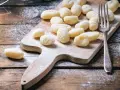 Gnocchi fatti in casa su tagliere di legno, spolverati di farina. L'impasto gnocchi troppo appiccicoso ha reso la preparazione un po' complicata, ma il risultato è invitante.