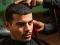 Mężczyzna z buzz cut i widocznymi zakolami w salonie fryzjerskim. Fryzjer przycina włosy.