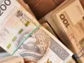 Stosy polskich banknotów 200 zł i 100 zł. Zastanawiasz się, ile zarabia sprzedawca w salonie samochodowym?