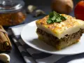Un assaggio di cosa mangiare ad Atene: moussaka fatta in casa, con strati di patate, carne macinata e besciamella dorata, guarnita con prezzemolo fresco.