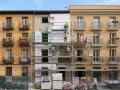 Obreros instalan aislamiento térmico en fachada de edificio. Se ve el **sate lana de roca** en bloques blancos, andamios y materiales de construcción.