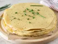 Pila di piadine di ceci dorate, guarnite con erba cipollina fresca. Perfette per un pasto leggero e gustoso.