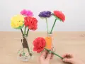 Flores de colores hechas con manualidades de papel de seda, en jarrones decorados.