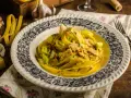 Makaron tagliatelle w kremowym sosie curry z kurczakiem i porem, ozdobiony szczypiorkiem.
