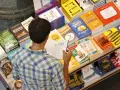 Hombre en una librería, rodeado de libros sobre finanzas y negocios, buscando las mejores editoriales para publicar un libro.
