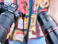 Dwie ręce trzymają obiektywy do Canona. Jeden z nich to Canon RF 135mm f/1.8L IS USM, drugi to Canon EF 135mm f/2L USM.