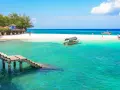 Zanzibar - wczasy opinie: turkusowa woda, biała plaża, drewniany pomost i łodzie. Rajskie widoki idealne na wakacje.
