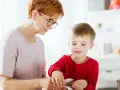 Babcia pomaga wnuczkowi w zajęciach, które mogą być częścią terapii stereotypii ruchowych.