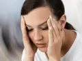 Kobieta zamyka oczy, masując skronie. Czuje silne zawroty głowy, świat wokół wiruje.