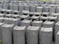 Rzędy betonowych bloczków, gotowych na fundamenty. Wybór między bloczkami z betonu a wylewanymi fundamentami jest kluczowy dla trwałości budowli.