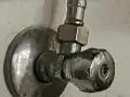 Metalowy zawór wodny, pokazujący, jak odkrecic zawor z woda. Widoczny śrubunek i pokrętło.