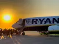 Zachód słońca nad lotniskiem, pasażerowie wsiadają do samolotu Ryanair. Marzysz o tanich podróżach? Ryanair loty za 1 zł to szansa na przygodę!