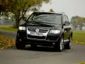 Czarny VW Touareg 2.5 TDI R5 na jesiennej drodze. Choć to solidne auto, warto znać jego potencjalne wady.