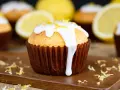 Zitronenmuffins mit weißer Glasur und Zitronenschale, die an eine Backmischung für Zitronenmuffins erinnern.