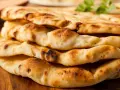 Gestapeltes, frisch gebackenes Naan Brot mit leichten Röststellen. Perfekt zum Dippen!