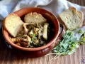 Seppie in zimino, un piatto tradizionale con seppie tenere e verdure, servito in una ciotola di terracotta con pane tostato e erbe aromatiche.