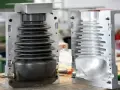 Two halves of a mold for compression molding products, one showing a black bellows-like component, the other an empty cavity.