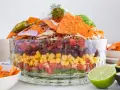 Schichtsalat mit Tortilla-Chips, Bohnen, Mais, Tomaten und Hackfleisch. Ein köstlicher, vegetarischer Nacho Salat, garniert mit Jalapeños und Sauerrahm.