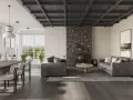 Salón moderno con chimenea de piedra, sofás grises y techos oscuros de madera que crean un ambiente acogedor.