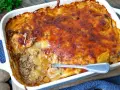Omas Kartoffelauflauf mit Hackfleisch, goldbraun überbacken, dampft in einer weißen Auflaufform. Eine Gabel steckt in der saftigen Schicht.