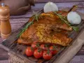 Carne marinada, lista para cocinar. El secreto ibérico se revela con romero, tomates y cebolla.