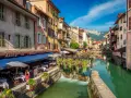 Canal animé à Annecy, avec des restaurants en terrasse et des fleurs colorées. Idéal pour découvrir les choses à faire à Annecy.