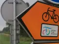 Pomarańczowy znak kierunkowy z rowerem i napisem "Wiślana Trasa Rowerowa" wskazuje drogę.